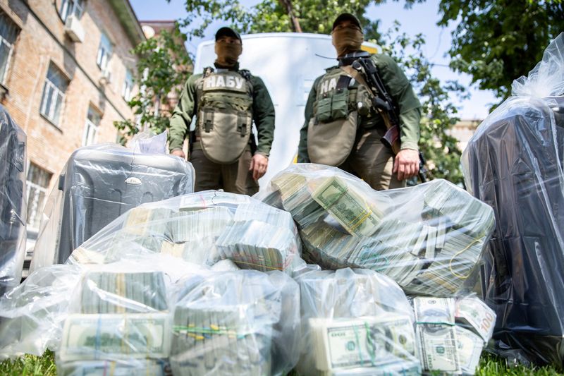 © Reuters. Officers of the National Anti-Corruption Bureau of Ukraine stand next to plastic bags filled with seized U.S. Dollar banknotes in Kiev, Ukraine, in this handout picture released June 13, 2020. Press Service of the National Anti-Corruption Bureau of Ukraine/Handout via REUTERS/File Photo