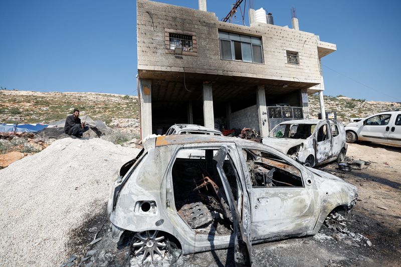 © Reuters. A Palestinian man sits near a damaged house and damaged cars after Israeli settlers attacked the village of al-Mughayyer, in the Israeli-occupied West Bank, April 13, 2024. REUTERS/Mohammed Torokman/File Photo