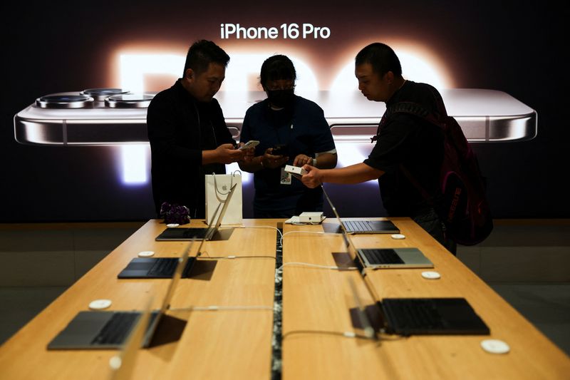 &copy; Reuters. A staff member attends to customers as the new iPhone 16 series go on sale at an Apple store in Beijing, China September 20, 2024. REUTERS/Florence Lo