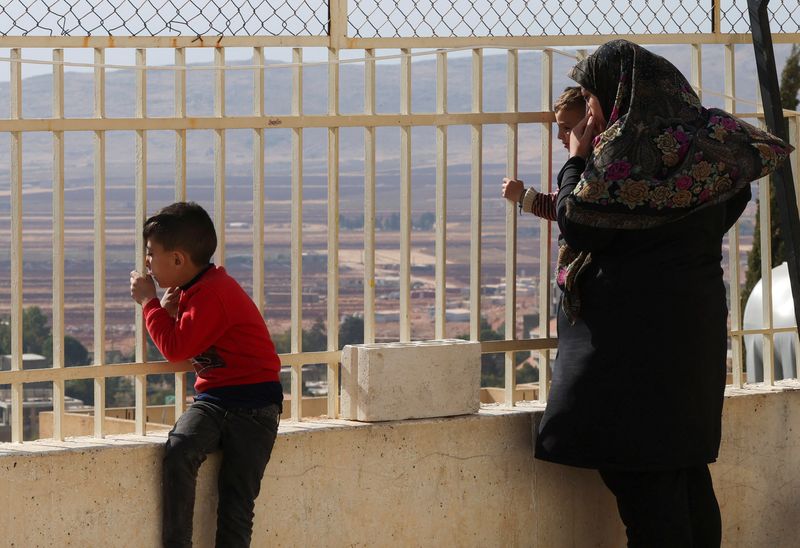 © Reuters. Displaced people look out from behind a fence at a school turned into a shelter housing displaced people who fled from Baalbek and surrounding areas, in the mountainous Christian town of Deir al-Ahmar in eastern Lebanon October 31, 2024. REUTERS/Mohamed Azakir