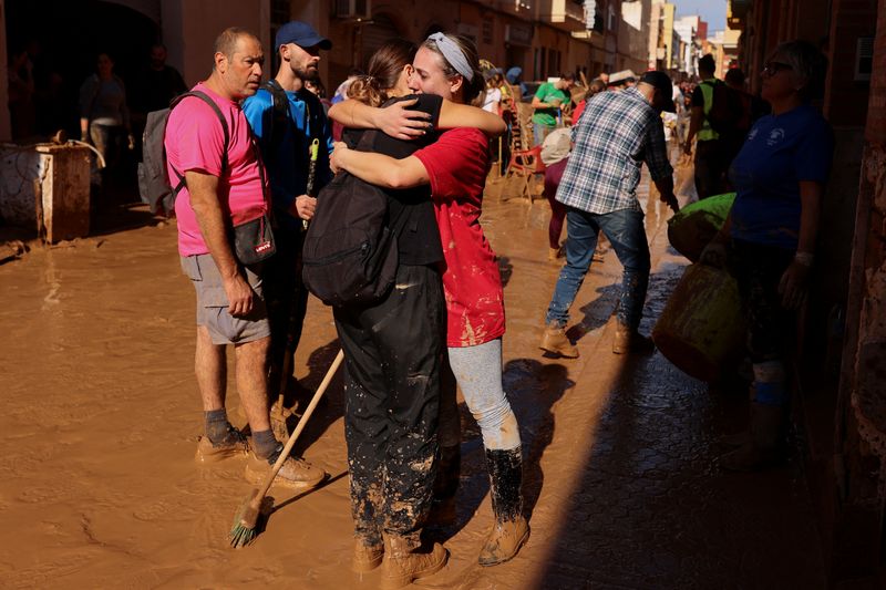 © Reuters. People hug each other as they stand on a street covered in mud following heavy rains that caused floods, in Paiporta, near Valencia, Spain, November 1, 2024. REUTERS/Nacho Doce