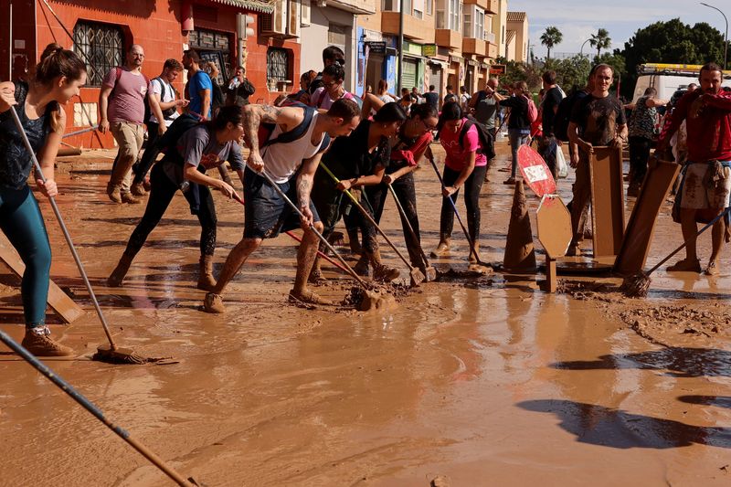 © Reuters. People sweep mud off the street following heavy rains that caused floods, in Paiporta, near Valencia, Spain, November 1, 2024. REUTERS/Nacho Doce