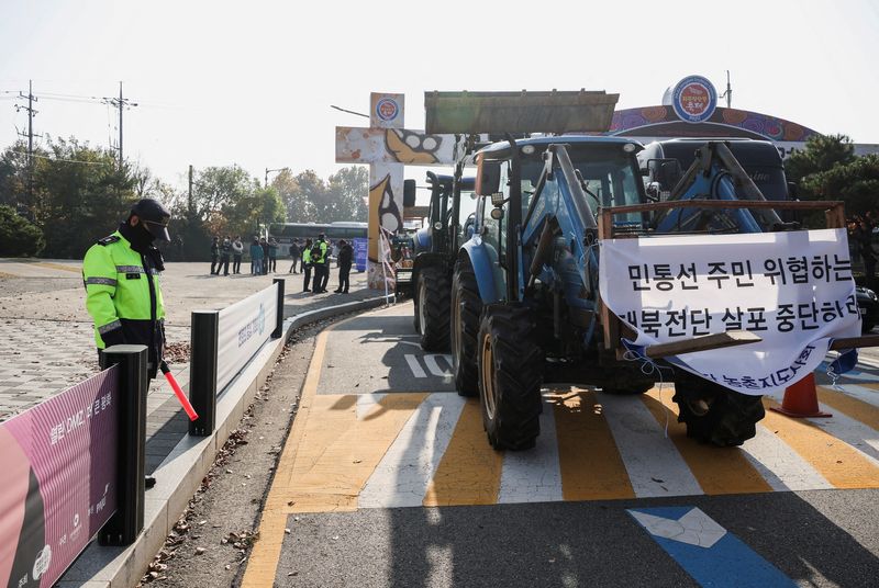 &copy; Reuters. FILE PHOTO: A policeman stands near tractors of farmers who live in villages near the Military Demarcation Line (MDL), inside the demilitarised zone separating the two Koreas, as the farmers take part in a protest against the launch of anti-North Korean l