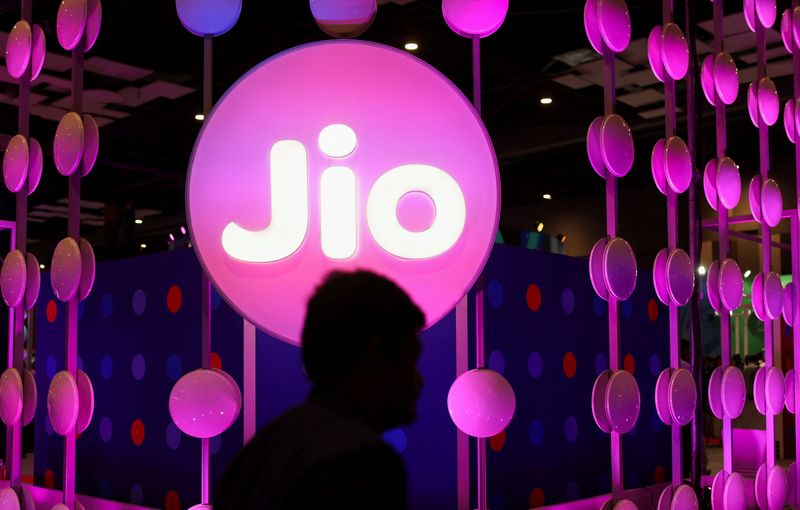 © Reuters. FILE PPHOTO: A man walks across the LED board showing the logo of Jio at the ongoing India Mobile Congress 2022, at Pragati Maidan, in New Delhi, India, October 3, 2022. REUTERS/Anushree Fadnavis/File Photo