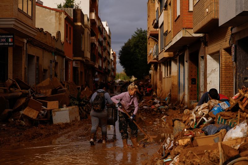 © Reuters. A woman cleans thick mud, in the aftermath of floods caused by heavy rains, in Sedavi, near Valencia, Spain, November 3, 2024. REUTERS/Susana Vera/File Photo