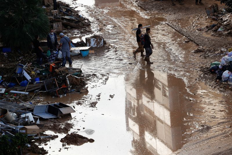 © Reuters. People walk on a mud-covered street, following heavy rains that caused floods, in Paiporta, near Valencia, Spain, November 4, 2024. REUTERS/Eva Manez