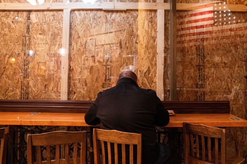 © Reuters. A person eats inside of a restaurant with plywood covering the windows near the White House in  Washington, U.S., November 4, 2024. REUTERS/Nathan Howard