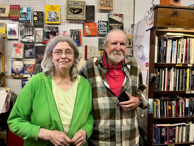 © Reuters. Martha Sempliner and John Veverka, both supporters of Vice President Kamala Harris, pose for a picture behind the counter at the Library Bookstore in Ferndale, Michigan, U.S., November 3, 2024. REUTERS/Nathan Layne