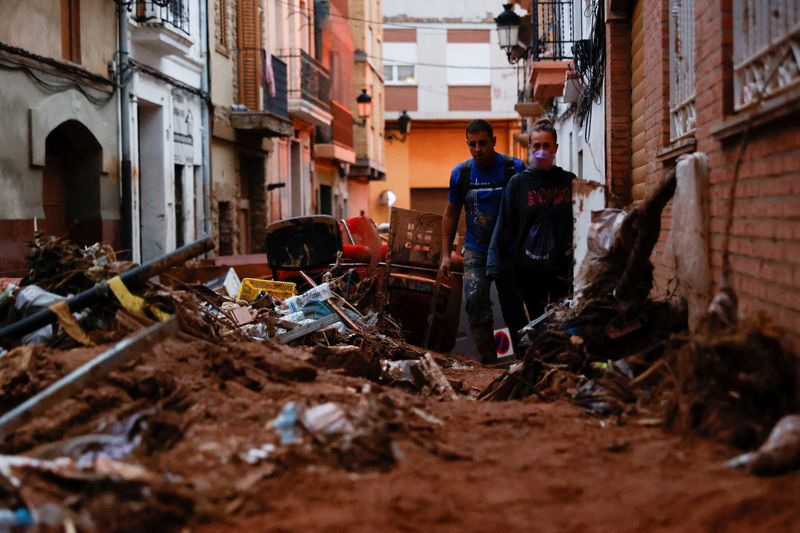 © Reuters. FILE PHOTO: People walk through mud in a street, following heavy rains that caused floods, in Paiporta, near Valencia, Spain, November 4, 2024. REUTERS/Eva Manez/File Photo