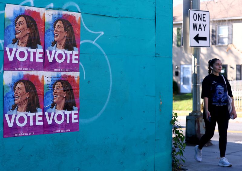 © Reuters. A woman walks past signs encouraging people to vote for Democratic presidential nominee and U.S. Vice President Kamala Harris in Washington, US, October 31, 2024. REUTERS/Hannah McKay/File Photo