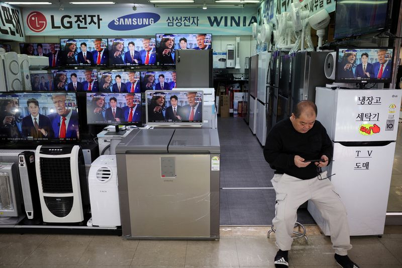 © Reuters. A shop owner sits in front of a set of TVs broadcasting a live news report on the U.S. election, in Seoul, South Korea, November 6, 2024.   REUTERS/Kim Hong-Ji