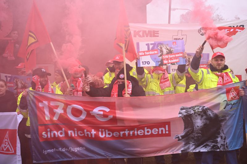 © Reuters. Employees of Volkswagen AG burn red flares during protests and a 'warning strike' of Germany's IG Metall metalworkers' union, in Osnabrueck, Germany, November 6, 2024. The placard reads, “170 Euro more are not exaggerated”.  REUTERS/Teresa Kroeger