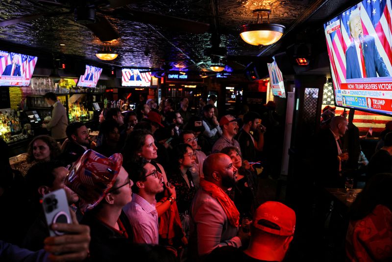 © Reuters. Supporters of Republican presidential nominee former U.S. President Donald Trump look at screens showing Trump speak from the Palm Beach County Convention Center, as they attend the New York Young Republican Club watch party during the 2024 U.S. presidential election, in Manhattan, New York City, U.S., November 6, 2024. REUTERS/Andrew Kelly