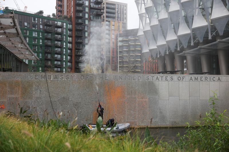 © Reuters. People use a pressure washer to wash orange paint off a sign outside the U.S. embassy in London, Britain, November 6, 2024. REUTERS/Mina Kim