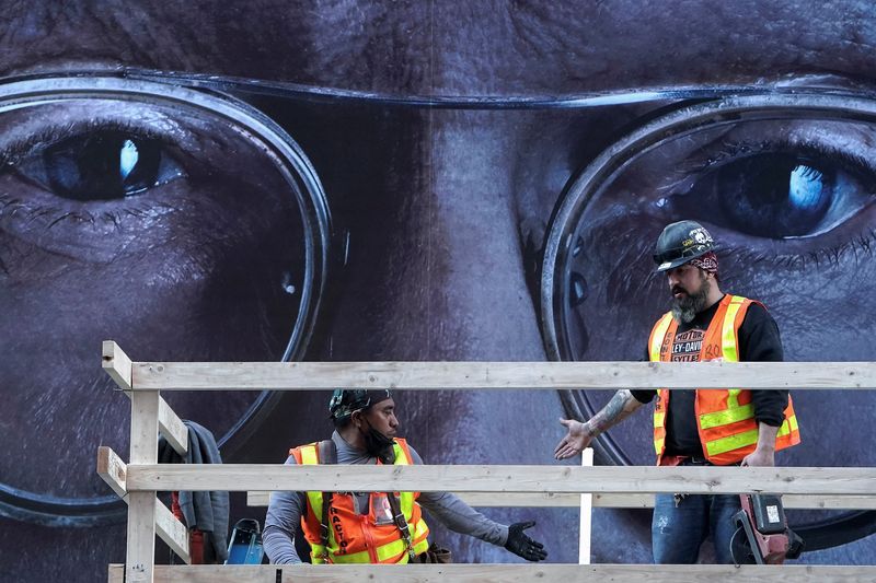 © Reuters. Construction workers build a structure in front of a poster of actor Larry David in Times Square in the Manhattan borough of New York City, New York, U.S., November 18, 2021.  REUTERS/Carlo Allegri/File Photo