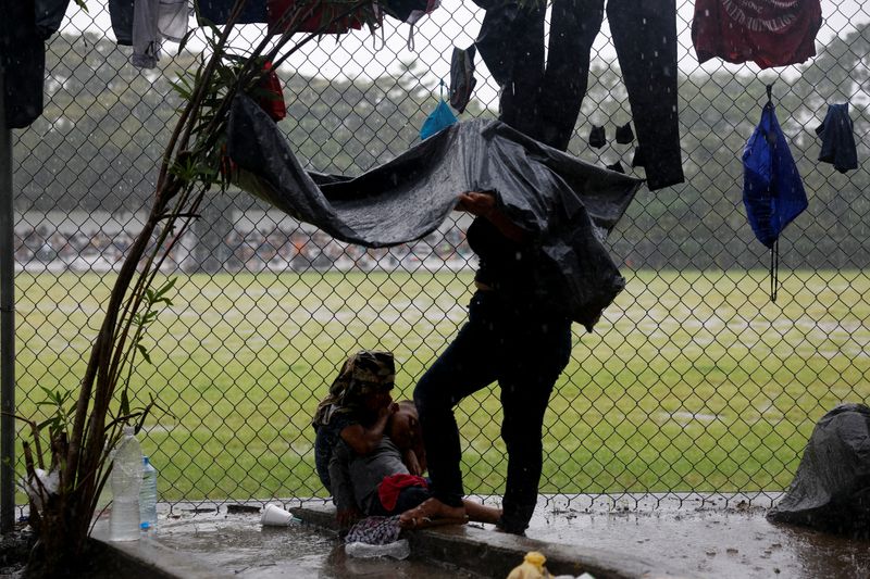 © Reuters. Migrants in a caravan shelter from the rain while they rest before continuing on their way to the U.S. border, in Escuintla, Mexico November 7, 2024. REUTERS/Daniel Becerril