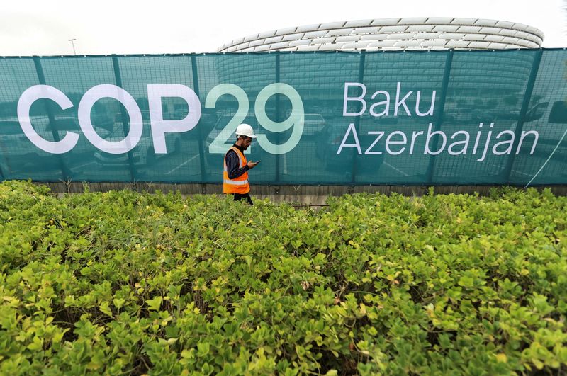 © Reuters. FILE PHOTO: A worker walks along a fence near the Baku Olympic Stadium, the venue of the COP29 United Nations Climate Change Conference, in Baku, Azerbaijan October 18, 2024. REUTERS/Aziz Karimov//File Photo