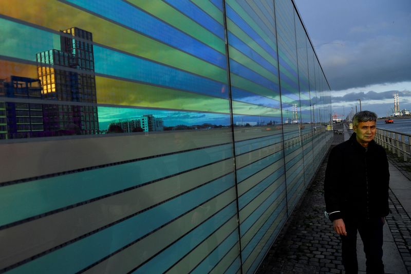 © Reuters. FILE PHOTO: A man walks past a reflective building showing the Grand Canal Docks area of Dublin, Ireland, February 11, 2022. REUTERS/Clodagh Kilcoyne/File Photo