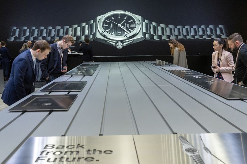 © Reuters. FILE PHOTO: Visitors look at models at the IWC booth during the Watches and Wonders exhibition in Geneva, Switzerland March 27, 2023. REUTERS/Denis Balibouse/File Photo