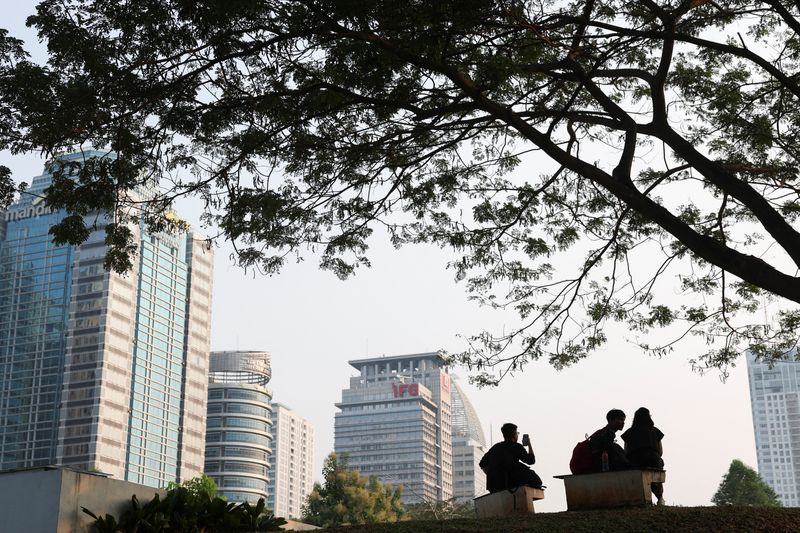 © Reuters. FILE PHOTO: People sit at a park with a view of buildings in the Sudirman Central Business District (SCBD) area in Jakarta, Indonesia, July 31, 2024. REUTERS/Ajeng Dinar Ulfiana/File Photo