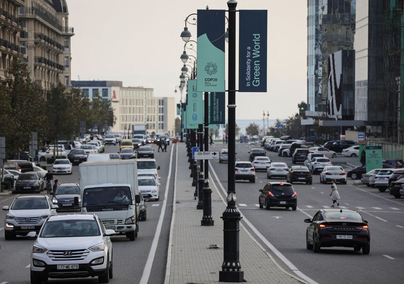 © Reuters. FILE PHOTO: Vehicles drive past the COP29 United Nations Climate Change Conference posters, in Baku, Azerbaijan October 31, 2024. REUTERS/Aziz Karimov/File Photo