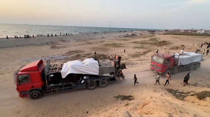 © Reuters. FILE PHOTO: Trucks carrying aid delivered into Gaza via a U.S.-built pier move, as seen from central Gaza Strip, in this still image taken from a video, May 17, 2024. REUTERS/Reuters TV/File Photo