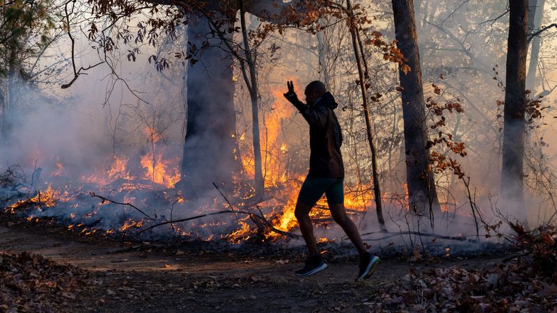 &copy; Reuters. A morning jogger gestures as he runs past a fire lit by members of the New Jersey Forest Fire Service as part of back burning efforts alongside Palisades Interstate Parkway in Englewood Cliffs, New Jersey, U.S., November 8, 2024. Julian Leshay Guadalupe/N