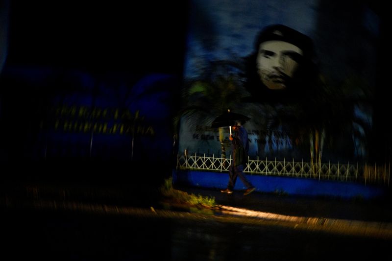 &copy; Reuters. Homem passa por uma imagem do falecido herói revolucionário Ernesto "Che" Guevara durante um apagão após o furacão Rafael derrubar a rede elétrica do país, em Havana, Cuban07/11/2024nREUTERS/Norlys Perez