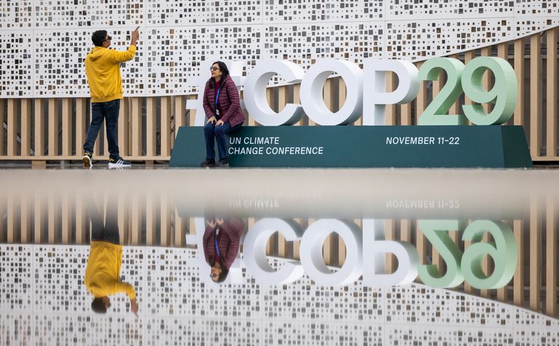 &copy; Reuters. Pessoas tiram fotos na entrada do local da conferência da ONU de mudanças climáticas (COP29), antes do início da cúpula em Baku, Azerbaijão n10/11/2024nREUTERS/Maxim Shemetov