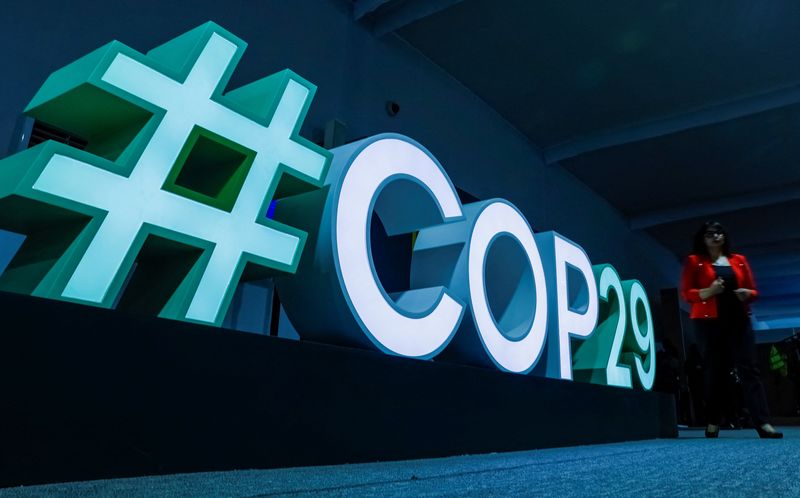 © Reuters. A woman passes by a #COP29 sign during the United Nations climate change conference COP29 in Baku, Azerbaijan November 11, 2024. REUTERS/Maxim Shemetov