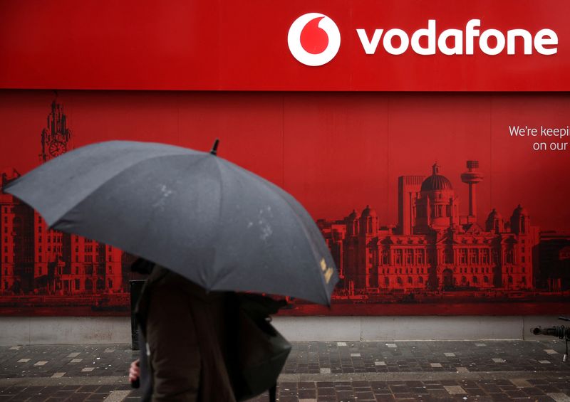 &copy; Reuters. Un uomo passa con un ombrello davanti a un negozio di telefonia mobile Vodafone a Liverpool, in Gran Bretagna, l'8 ottobre 2024. REUTERS/Phil Noble