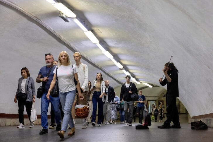 © Reuters. A man plays the violin as people walk in a subway station during morning rush hour in central Kyiv, Ukraine, September 20, 2024.  REUTERS/Thomas Peter/File Photo