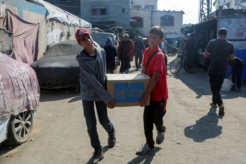 &copy; Reuters. Palestinesi trasportano una scatola di aiuti distribuita dall'Agenzia delle Nazioni Unite per il Soccorso e l'Occupazione (UNRWA), durante il conflitto tra Israele e Hamas, a Deir Al-Balah, nella Striscia di Gaza centrale, il 4 novembre 2024. REUTERS/Rama