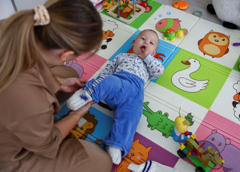 &copy; Reuters. Alina Rzhanova ajusta roupas do filho Igor durante entrevista em seu apartamento, em Yaroslavl, na Rússian03/10/2024nREUTERS/Evgenia Novozhenina