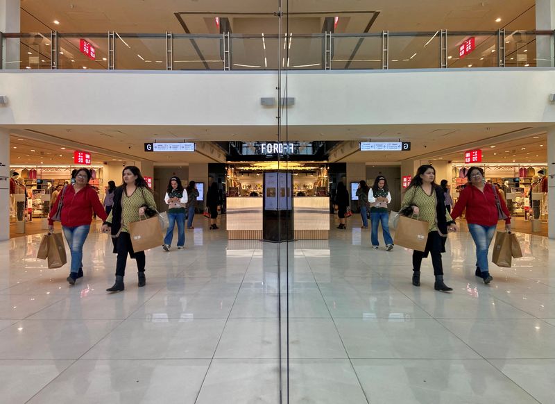 © Reuters. FILE PHOTO: Shoppers are reflected in mirror inside a shopping mall in New Delhi, India, December 14, 2022. REUTERS/Anushree Fadnavis/File Photo