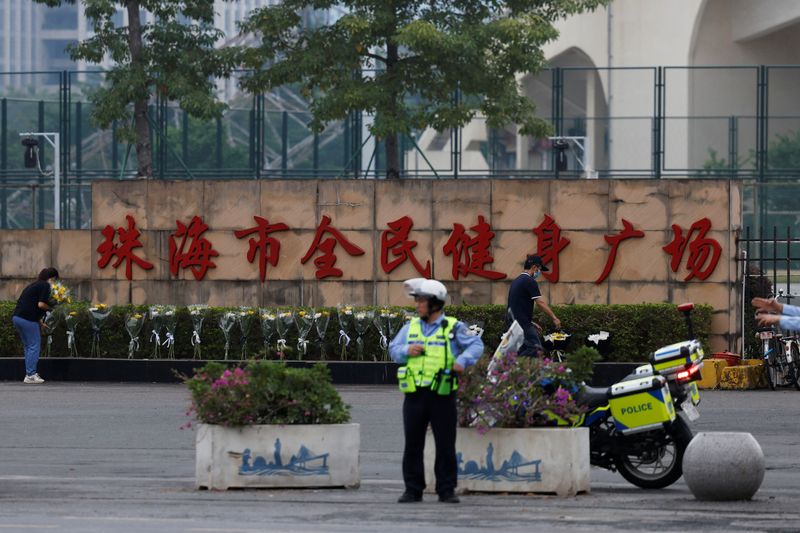 &copy; Reuters. A police officer keeps watch as people remove flower bouquets placed outside the sports centre where a deadly car attack took place, in Zhuhai, Guangdong province, China November 13, 2024. REUTERS/Tingshu Wang