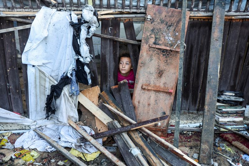 &copy; Reuters. A child looks on as Palestinians inspect the site of an Israeli strike on tents of displaced people, in Deir Al-Balah in the central Gaza Strip November 13, 2024. REUTERS/Ramadan Abed   