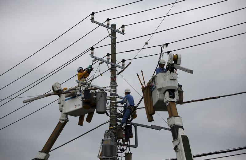 &copy; Reuters. FILE PHOTO: Men work around an electric utility pole along the street in Urayasu, east of Tokyo October 9, 2014. REUTERS/Issei Kato/File Photo