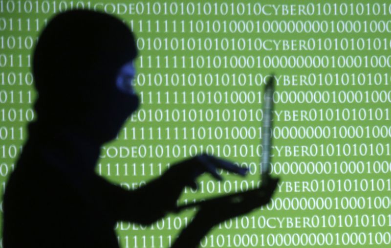 © Reuters. FILE PHOTO: A person wearing a balaclava is silhouetted as he poses with a laptop in front of a screen projected with the word 'cyber' and binary code, in this picture illustration taken in Zenica October 29, 2014. REUTERS/Dado Ruvic/File Photo