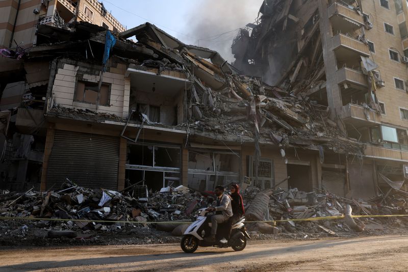 © Reuters. People ride a scooter past damaged buildings, in the aftermath of Israeli strikes on Beirut's southern suburbs, during a Hezbollah media tour, amid the ongoing hostilities between Hezbollah and Israeli forces, Lebanon, November 9, 2024. REUTERS/Mohamed Azakir/File Photo