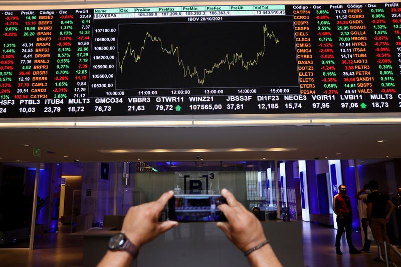 © Reuters. FILE PHOTO: A man takes a picture with his phone of an electronic board showing the recent fluctuations of market indices on Brazil's B3 Stock Exchange in Sao Paulo, Brazil October 28, 2021. REUTERS/Amanda Perobelli/File photo