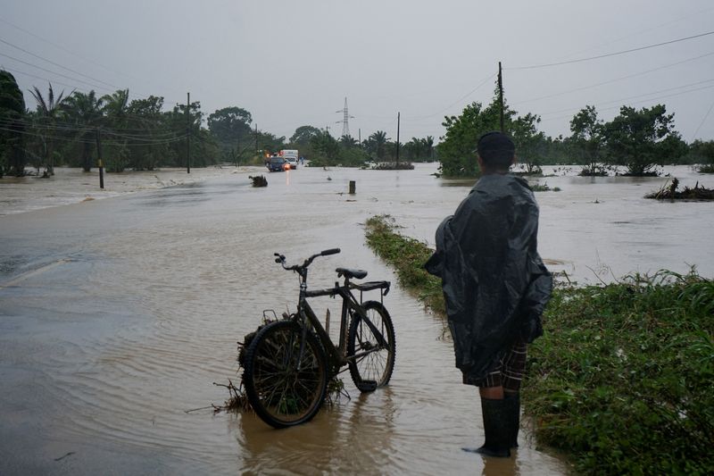 © Reuters. A man stands next to his bicycle on a flooded road after the Arizona River overflowed its banks due to heavy rain brought by Tropical Storm Sara, in Tela, Honduras November 15, 2024. REUTERS/Marvin Valladares