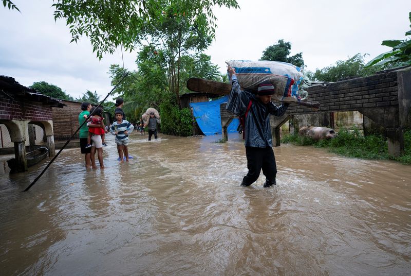 © Reuters. People walk along flooded streets in a community cut off by flooding from Tropical Storm Sara, in El Marion, Honduras, Nov. 16, 2024. REUTERS/Fritz Pinnow