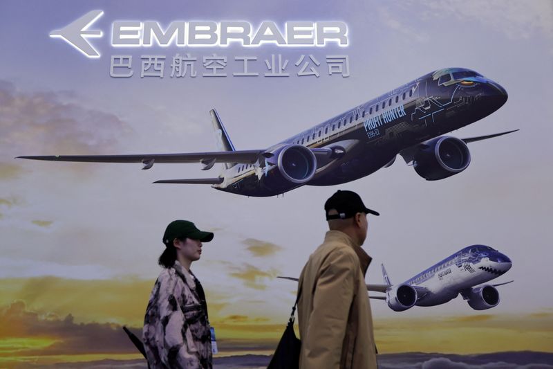 © Reuters. FILE PHOTO: People walk past a sign of the Brazilian planemaker Embraer at the China International Aviation and Aerospace Exhibition, or Airshow China, in Zhuhai, Guangdong province, China November 14, 2024. REUTERS/Tingshu Wang/File photo