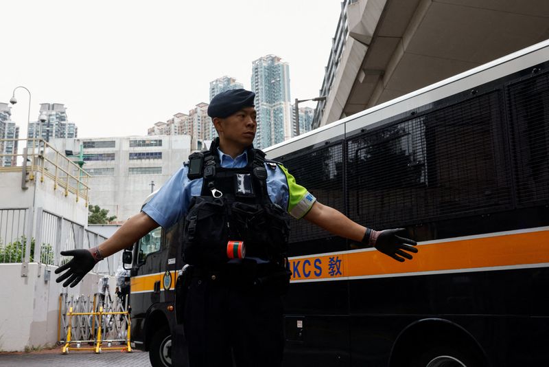 © Reuters. A police officer stands guard as a prison van arrives at the West Kowloon Magistrates' Courts building, ahead of the sentencing of 45 convicted pro-democracy activists charged under the national security law, in Hong Kong, China November 19, 2024. REUTERS/Tyrone Siu 