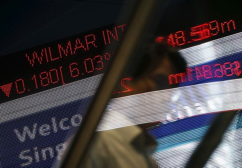 © Reuters. FILE PHOTO: A man passes a stock index board showing Wilmar International losing 6.03 percent at the Singapore Exchange in the central business district August 24, 2015. REUTERS/Edgar Su/File Photo