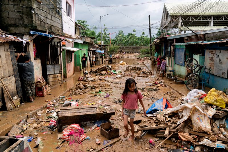 &copy; Reuters. FILE PHOTO: A girl walks past the debris and mud following the floods brought by Typhoon Gaemi, in Marikina City, Metro Manila, Philippines, July 25, 2024. REUTERS/Lisa Marie David/File Photo