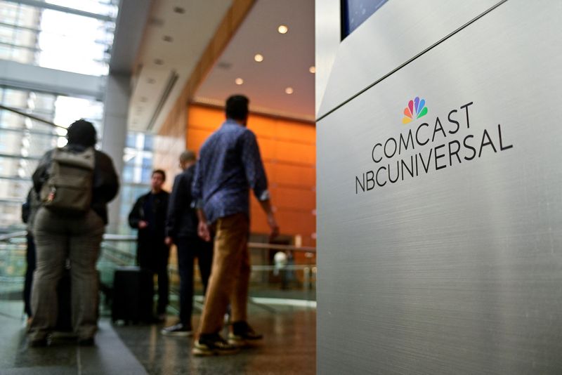 © Reuters. People stand near a signage of Comcast and NBC Universal in the lobby of the corporate headquarters of Comcast, which announced plans to spin-off the bulk of its fading NBCUniversal cable TV networks, including MSNBC and CNBC, in Philadelphia, Pennsylvania, U.S. November 20, 2024. REUTERS/Bastiaan Slabbers