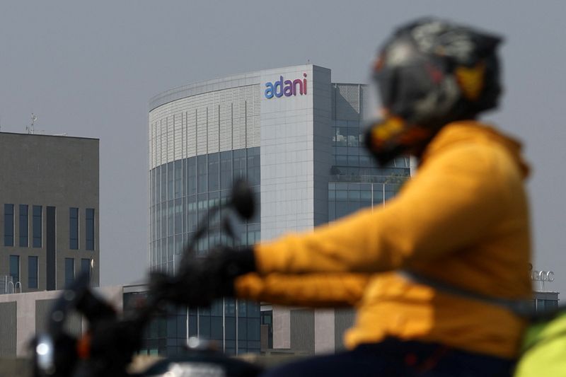 © Reuters. A man rides his motorbike past the Corporate House of Adani Group on the outskirts of Ahmedabad, India, November 21, 2024. REUTERS/Amit Dave