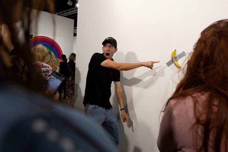 &copy; Reuters. Homem posa para foto ao lado de banana colada em parede com fita adesiva em Miamin07/12/2019 nREUTERS/Eva Marie Uzcategui